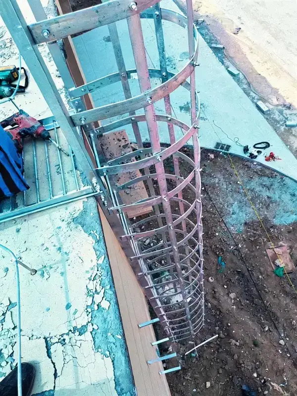 Échelle fixe verticale à arceaux circulaires vue de loin, cage de protection complète