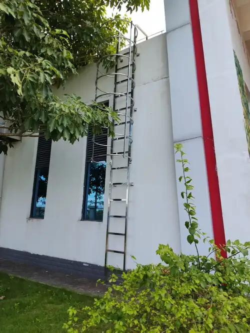 Échelle fixe verticale à cage de protection circulaire fixée à un bâtiment, vue d'ensemble